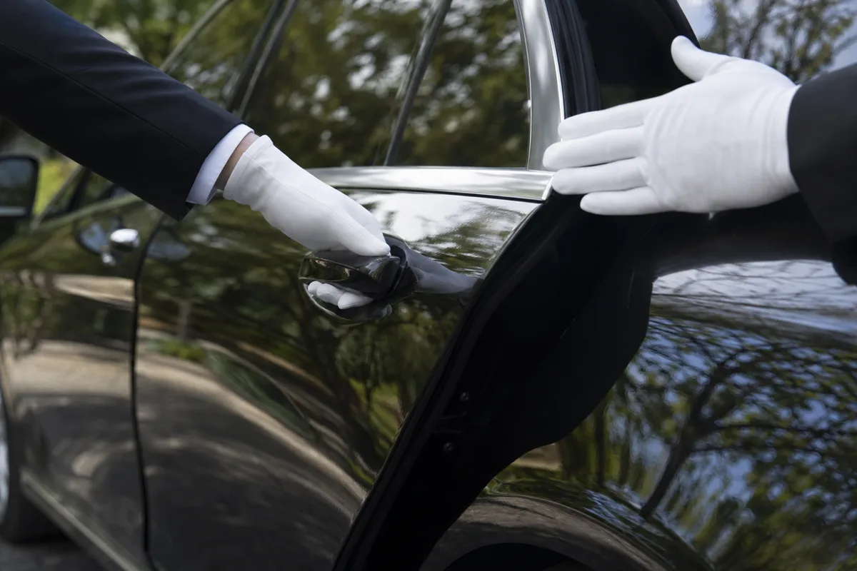 Mains d&rsquo;un chauffeur en gants ouvrant la portière d&rsquo;une limousine