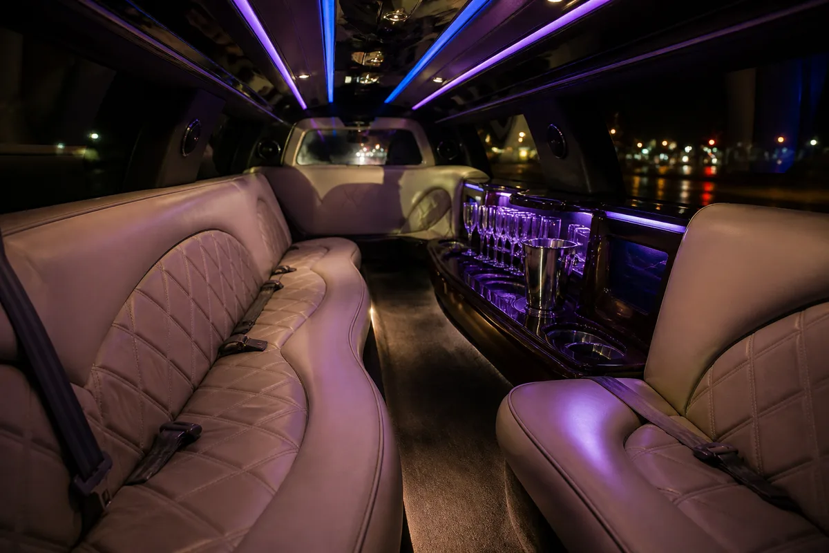 Intérieur d&rsquo;une limousine avec banquettes en cuir, éclairage led et coupes disposées sur la tablette centrale